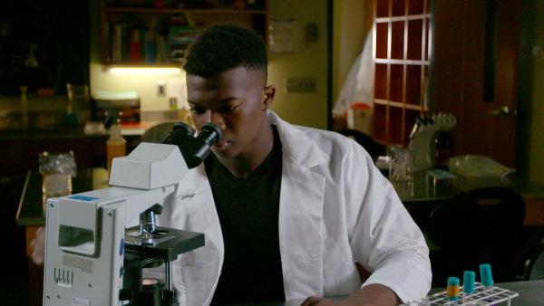 21岁的伊凡·伊顿博士通过显微镜观察